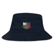 The NYC British and Irish Selects Crusher Bucket Cap by EMB S&S Activewear is a navy cotton twill bucket hat with an embroidered shield patch reading "NYC Welsh & Irish Select Rugby" in red, white, and green for stylish sun protection.