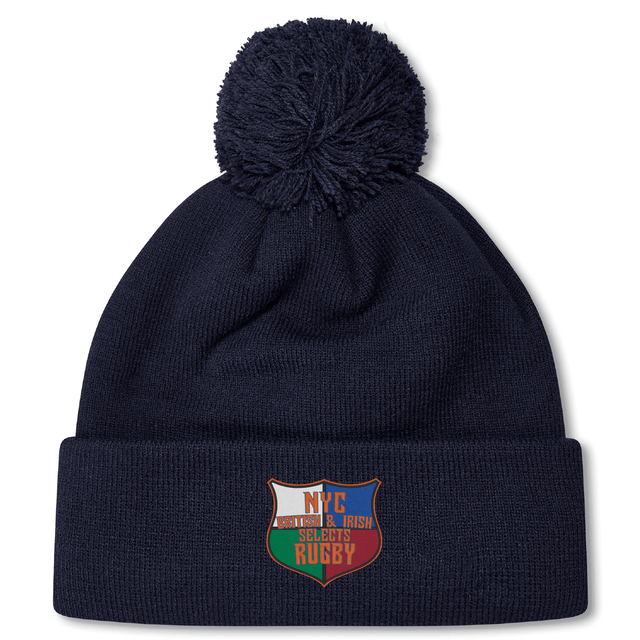 The NYC British and Irish Selects Pom Pom Beanie by EMB Canterbury is a stylish navy blue fleece-lined hat with a pom-pom, featuring an embroidered patch displaying a shield design and the text "NYC American & Irish Stouts Rugby.