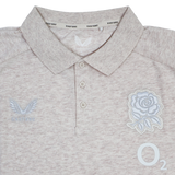 The England 26/27 Off-Pitch Polo by Castore features a beige design, three-button placket, rose emblem, Castore branding, and O2 logo—ideal for England Rugby fans looking for stylish off-pitch wear.