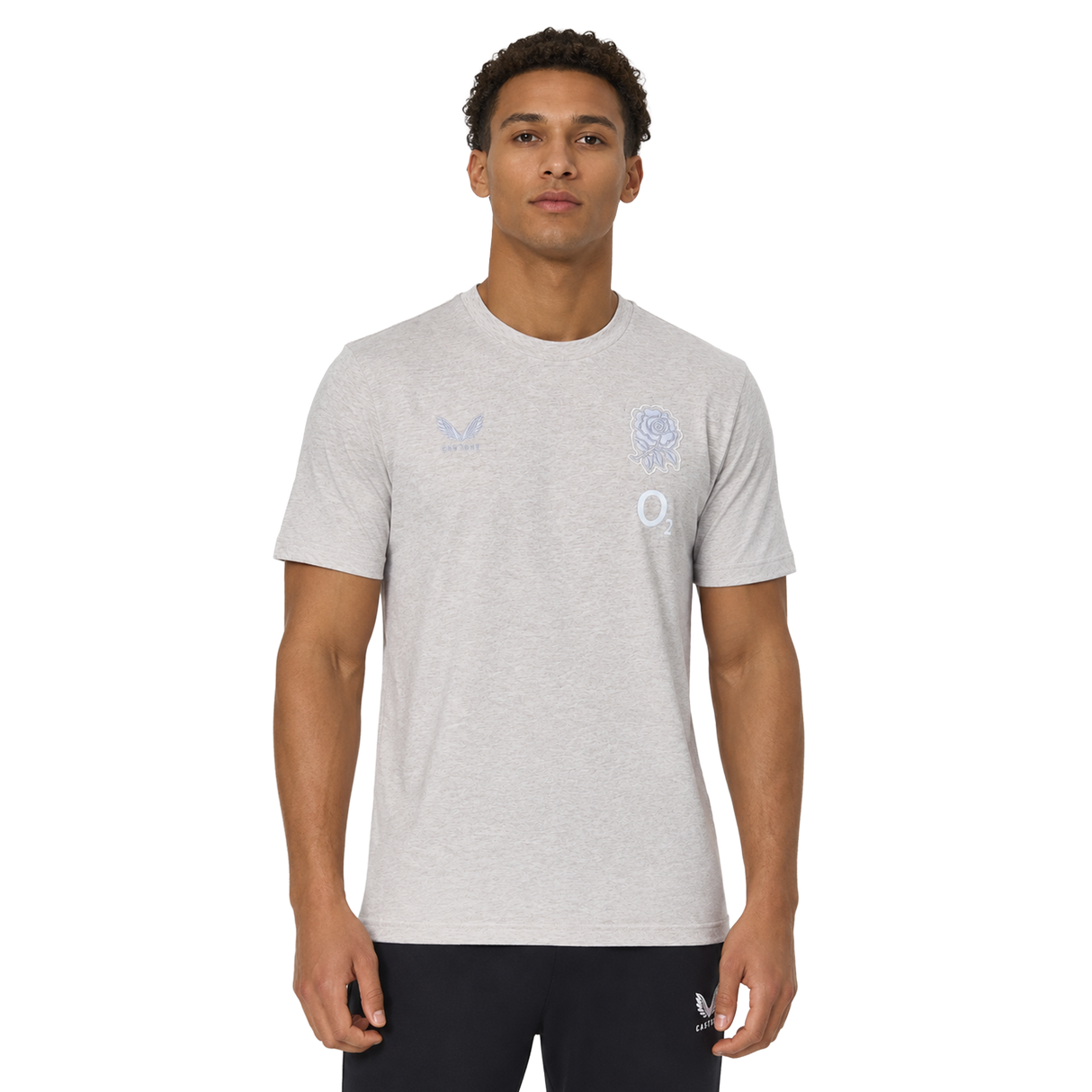 A man wears the England 26/27 Off-Pitch Tee by Castore, a light grey short-sleeve shirt with subtle chest logos, against a plain white background.