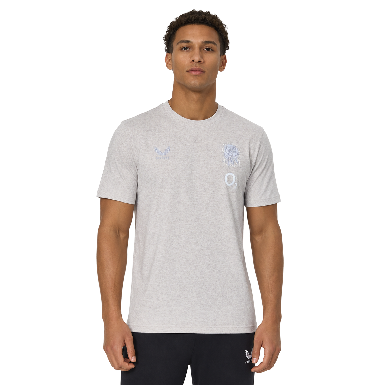 A man wears the England 26/27 Off-Pitch Tee by Castore, a light grey short-sleeve shirt with subtle chest logos, against a plain white background.