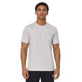 A man wears the England 26/27 Off-Pitch Tee by Castore, a light grey short-sleeve shirt with subtle chest logos, against a plain white background.