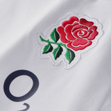 Close-up of an embroidered red rose with green leaves on the white England 26/27 Off-Pitch Tee by Castore, featuring part of a black printed letter.