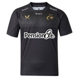 The Saracens 26/27 Replica Home Jersey by Castore is a sleek black short-sleeved jersey featuring gold logos and stars, “PensionBee” sponsor text on the front, and “StoneX” branding on the chest and shoulders.