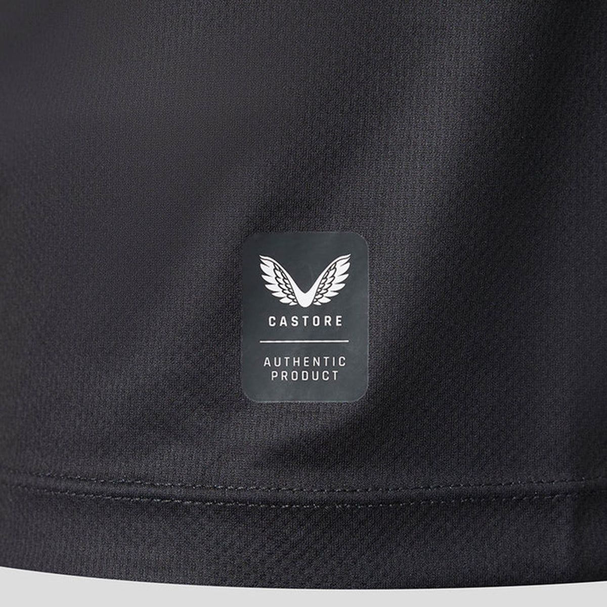 Close-up of a black fabric from the Saracens 26/27 Replica Home Jersey by Castore, showing a small label near a stitched seam featuring Castore’s winged logo and the text “AUTHENTIC PRODUCT.”.