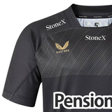 Close-up of the Saracens 26/27 Replica Home Jersey by Castore in black, highlighting the Castore logo, “StoneX” text, and a partial view of “Pension” on the front—showcasing details from the official 2026/27 home shirt.