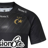 Here’s a rewritten version of the sentence, incorporating the provided product data: Close-up of the Saracens 26/27 Replica Home Jersey by Castore—a black shirt with bold gold accents, adorned with three stars and a crescent with a star, and displaying white “StoneX” and Castore sponsor logos.