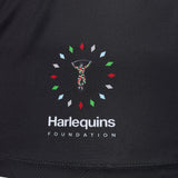 The Harlequins Foundation logo is displayed on black fabric and features a jester-like figure framed by colorful diamond shapes, with the “Harlequins Foundation” text below. This design draws inspiration from the iconic Harlequins 26/27 Replica Third Jersey by Castore and echoes the vibrant style characteristic of Castore’s celebrated rugby shirts.