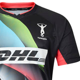 The Harlequins 26/27 Replica Third Jersey by Castore features a black design with vibrant colorful accents, the DHL sponsor logo, and the iconic Harlequins Rugby Club emblem with an acrobat silhouette on the upper left chest. Designed for dedicated fans, this Castore jersey captures the dynamic spirit of the Big Game 18 Shirt, making a bold statement both on and off the pitch.