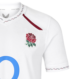 England 26/27 Replica Home Jersey by Castore—this white athletic rugby jersey features the iconic red rose emblem on the chest, maroon stitching on the collar and sleeves, and a partially visible blue “O,” authentically crafted as an official replica home jersey by Castore.