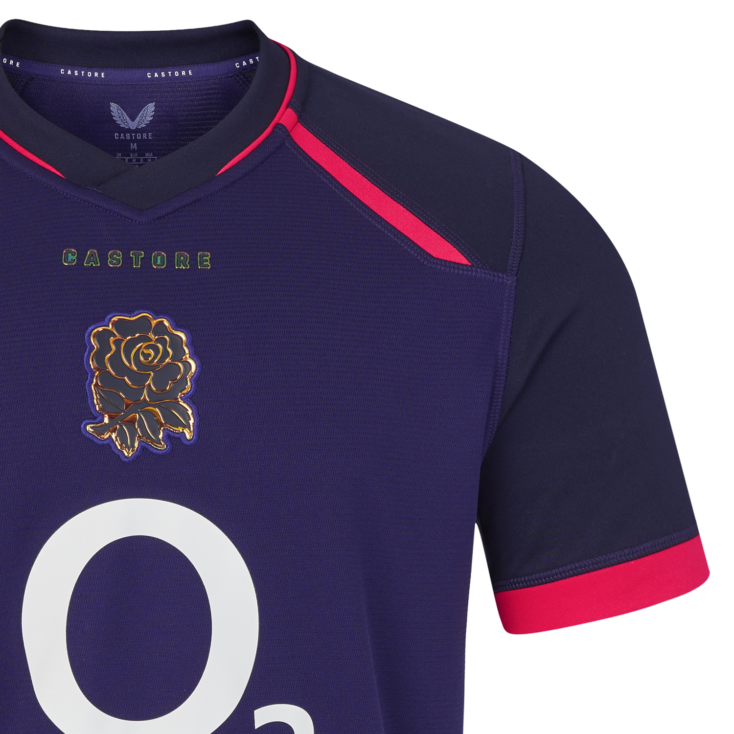 Close-up of the England 26/27 Replica Alternate Jersey by Castore: a navy blue shirt with pink accents, featuring a white “O2” logo and an embroidered gold rose emblem on the chest—a striking replica from Castore’s Rhodonite alternate kit.