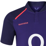 A close-up of the Castore England 26/27 Classic Alternate Jersey shows navy blue fabric, a bold red shoulder accent, and the number "0" partially visible on the front.