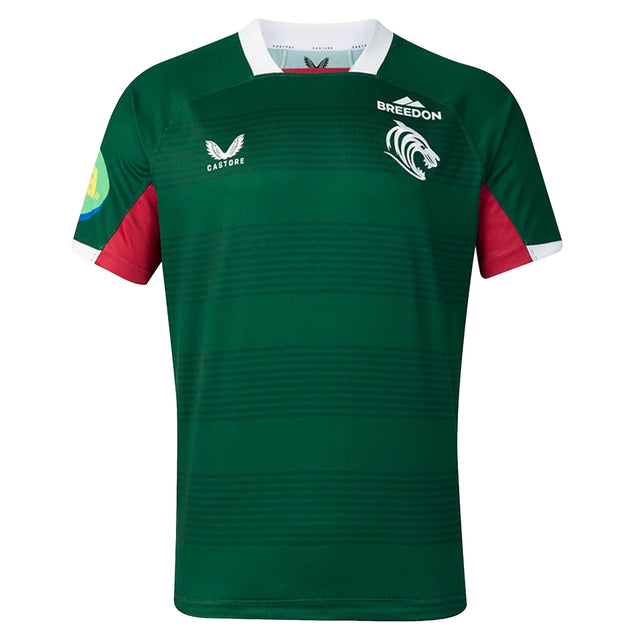 The Leicester 26/27 Replica Home Jersey by Castore features a green short-sleeved design with a white collar, red underarm panels, and distinctive logos such as Castore, Breedon, and a tiger emblem on the chest. This replica jersey by Castore authentically mirrors the official Leicester Tigers home kit for the 2026/27 season.