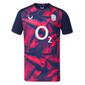 The England 26/27 Pre-Match Top by Castore is a short-sleeved shirt with a navy and bright pink geometric pattern, featuring the O2 logo and a white rose emblem on the chest.