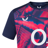 Close-up of the England 26/27 Pre-Match Top by Castore, showcasing bold red and blue abstract patterns, navy sleeves, a white "O" on the front, and the Castore logo near the collar.