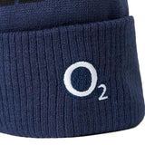 Close-up of the England 26/27 Bobble Beanie by Castore, a navy blue ribbed knit hat with a white embroidered “O₂” logo on the cuff—making it the perfect choice for any dedicated England rugby supporter throughout the winter season.