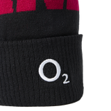 A close-up of the England 26/27 Bobble Beanie by Castore, featuring a black knit body with a red upper section and a white “O₂” logo embroidered on the folded cuff—this classic Castore beanie is the perfect winter accessory for any England rugby supporter.