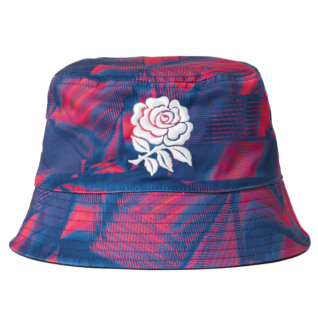 The Castore England 26/27 Reversible Bucket Cap features blue and red patterns and a white embroidered rose on the front, taking inspiration from the iconic England rugby cap.