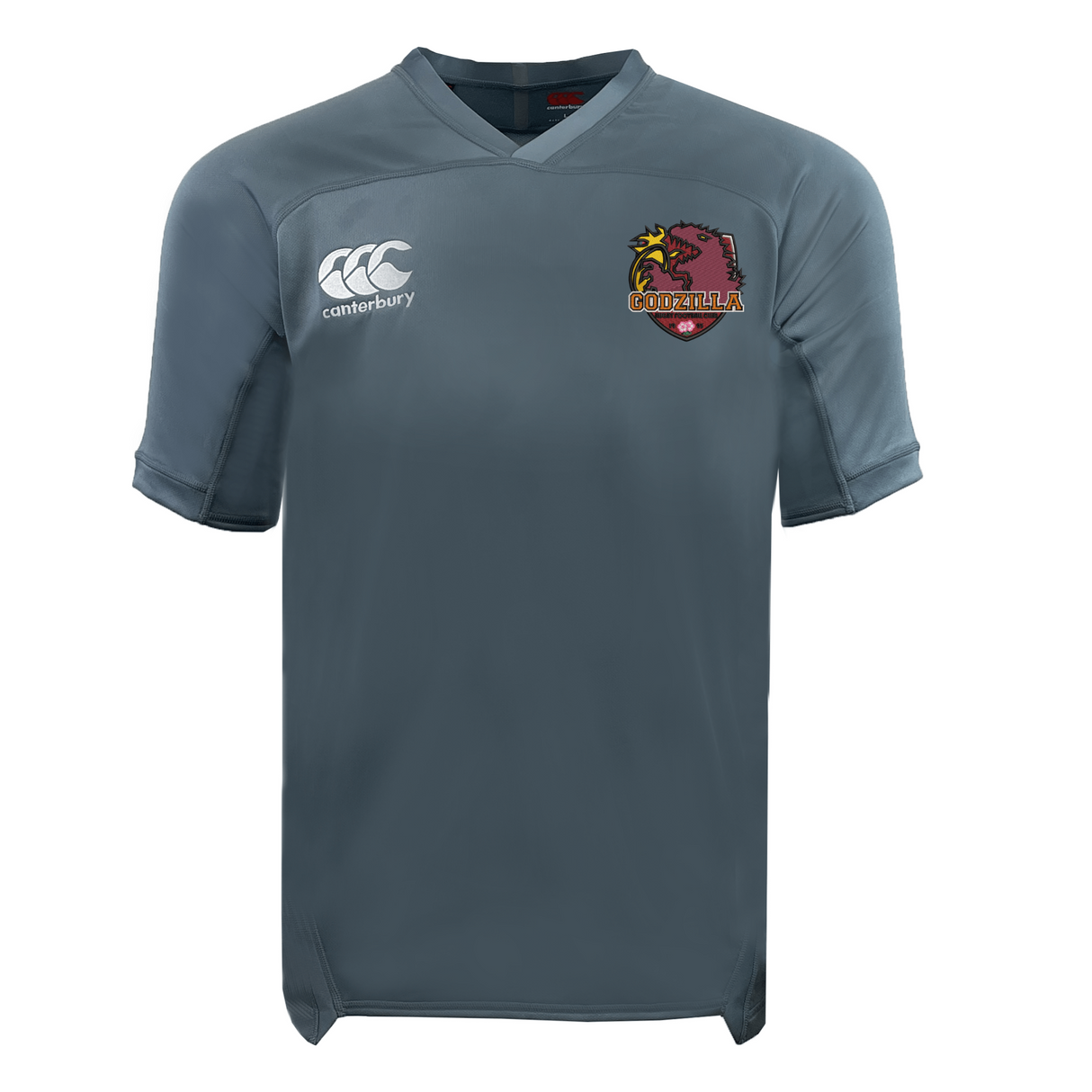 The Godzilla Rugby Football Club Vapodri Evader Jersey by EMB Canterbury is a plain gray short-sleeved rugby jersey featuring moisture-wicking Vapodri technology, with the Canterbury logo on the right chest and an embroidered “Godzilla” badge with a red creature on the left chest.