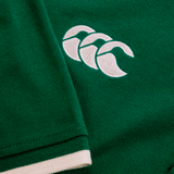 Close-up of a green fabric with a white embroidered logo featuring three overlapping shapes, reminiscent of the craftsmanship on an Ireland 24 Team Polo by Canterbury, complete with ribbed collar and cuffs.