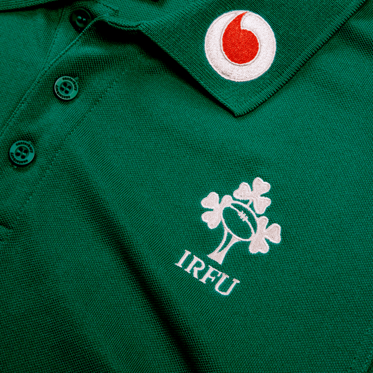 The Ireland 24 Team Polo by Canterbury features a green design with a ribbed collar and cuffs, adorned with the IRFU logo featuring a shamrock and rugby ball, plus embroidered sponsor logos.