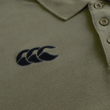 Close-up of the Ireland 25/26 Team Polo by Canterbury in olive green, featuring a collar, three buttons, and a black embroidered logo with three overlapping shapes on the left chest.