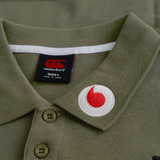 Close-up of the Ireland 25/26 Team Polo by Canterbury in olive green, size L, with a red and white circular patch near the collar—a must-have authentic rugby polo for fans.