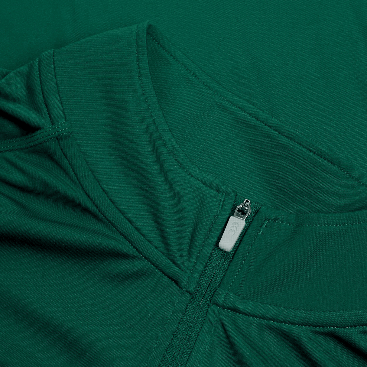 Close-up of a green Ireland 24 Vapodri First Layer by Canterbury, highlighting its zippered neckline with a pull tab. The smooth, fitted fabric showcases Canterbury's advanced VapoDri technology.