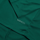 Close-up of green fabric featuring the word "VAPODRI" printed in small white letters. The image showcases the texture and stitching of the Ireland 24 Vapodri First Layer by Canterbury, highlighting Vapodri technology.