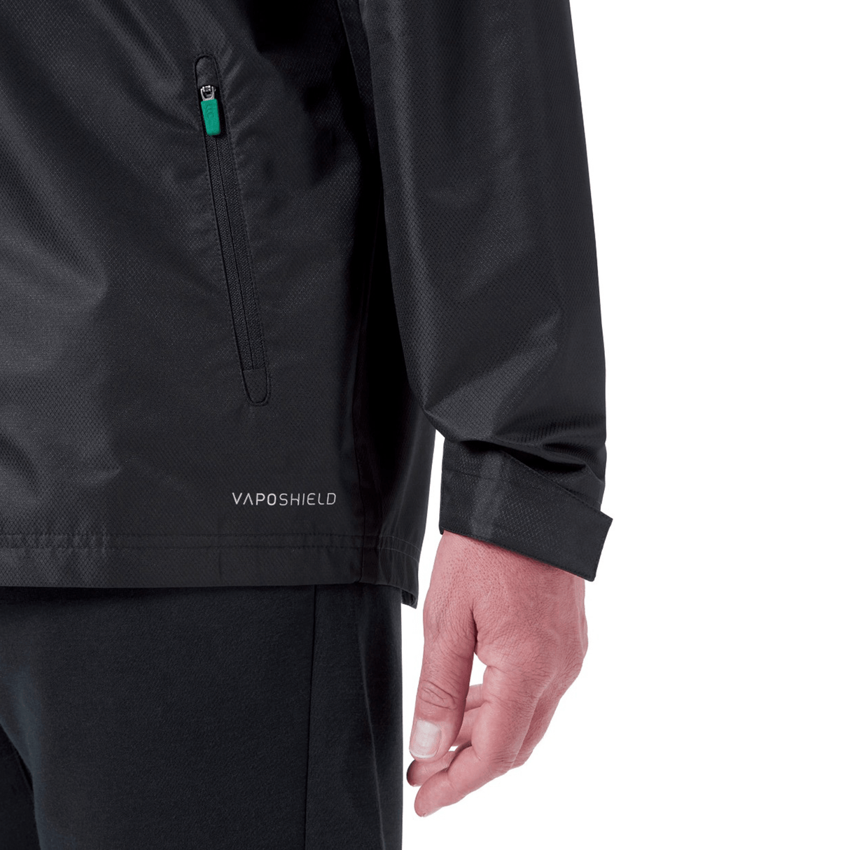 Close-up of a person wearing the Ireland 24 Wind Resistant Jacket by Canterbury, marked with "Vaposhield" near the hem. The jacket features a zippered pocket on the side, along with part of the person's arm and hand visible in the shot.