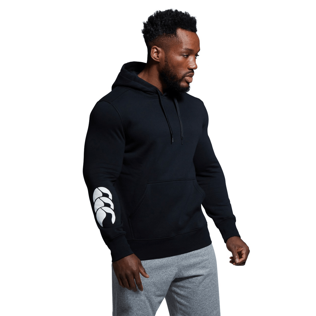 A man wearing a custom Canterbury Club Hoodie with sleeve branding, paired with sweatpants.