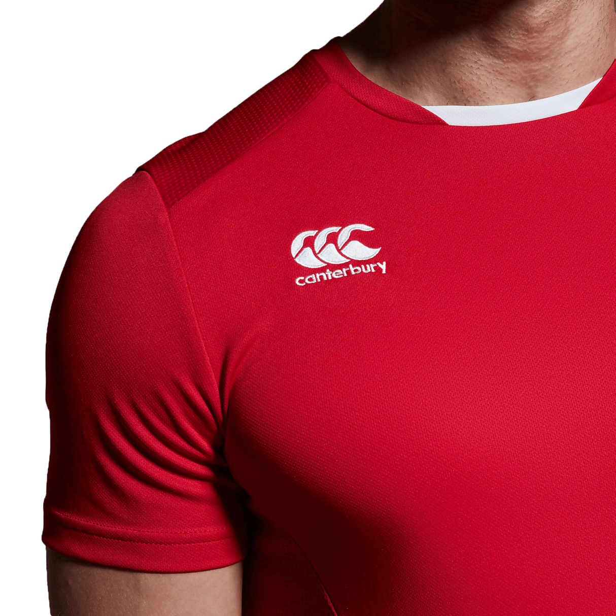 A man wearing a red Canterbury Club Dry Tee with a white logo.