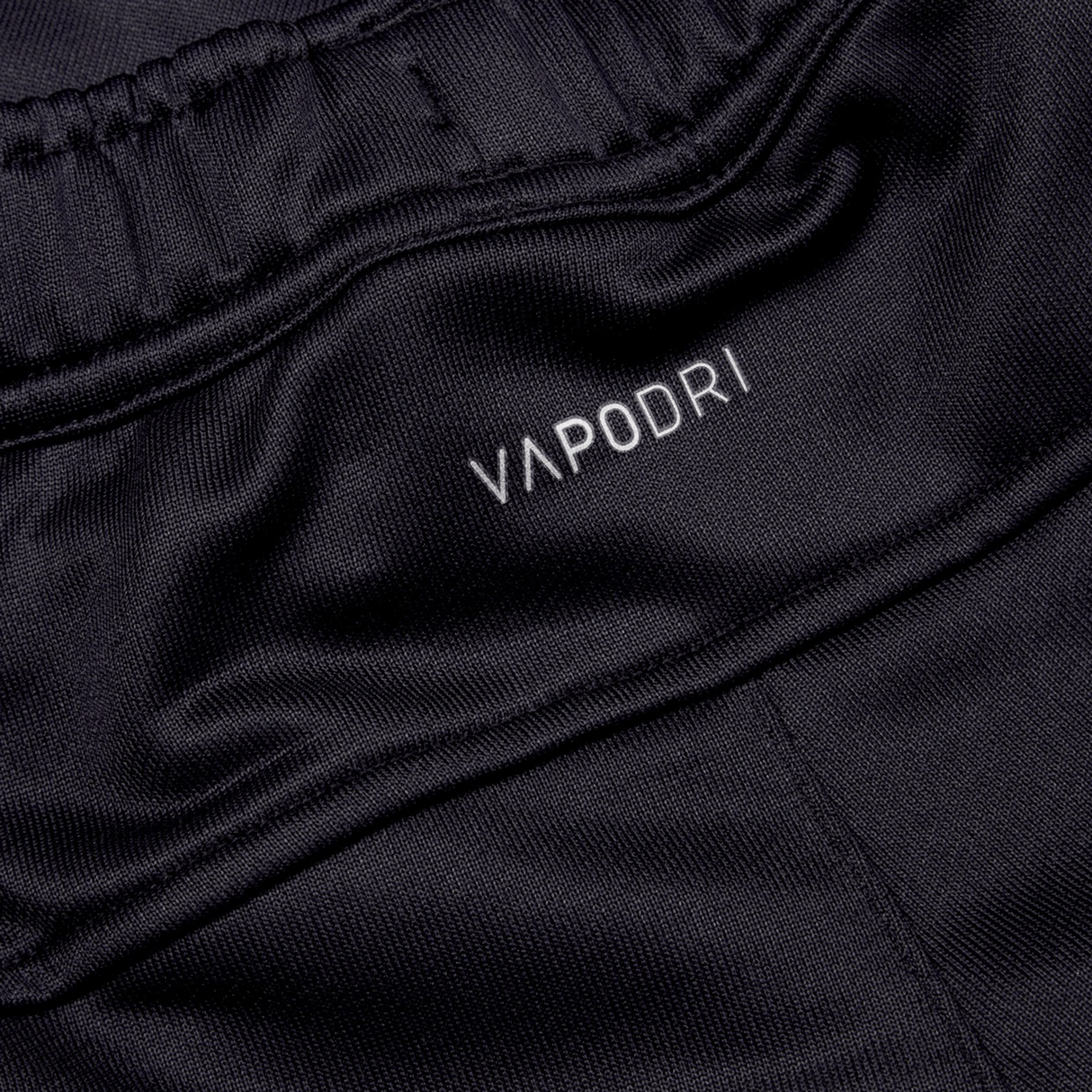 Close-up of the black athletic fabric labeled "Canterbury," showcasing an elastic waistband and smooth, breathable texture. Perfect for the Irish rugby fan, these Ireland 24 Poly Knit Pants by Canterbury incorporate VapoDri technology, ensuring comfort during intense matches.