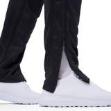 Close-up of an Irish rugby fan wearing Ireland 24 Poly Knit Pant by Canterbury with a zipper at the ankle and white lightweight athletic shoes. The pants are slightly open at the zipper, revealing white socks.