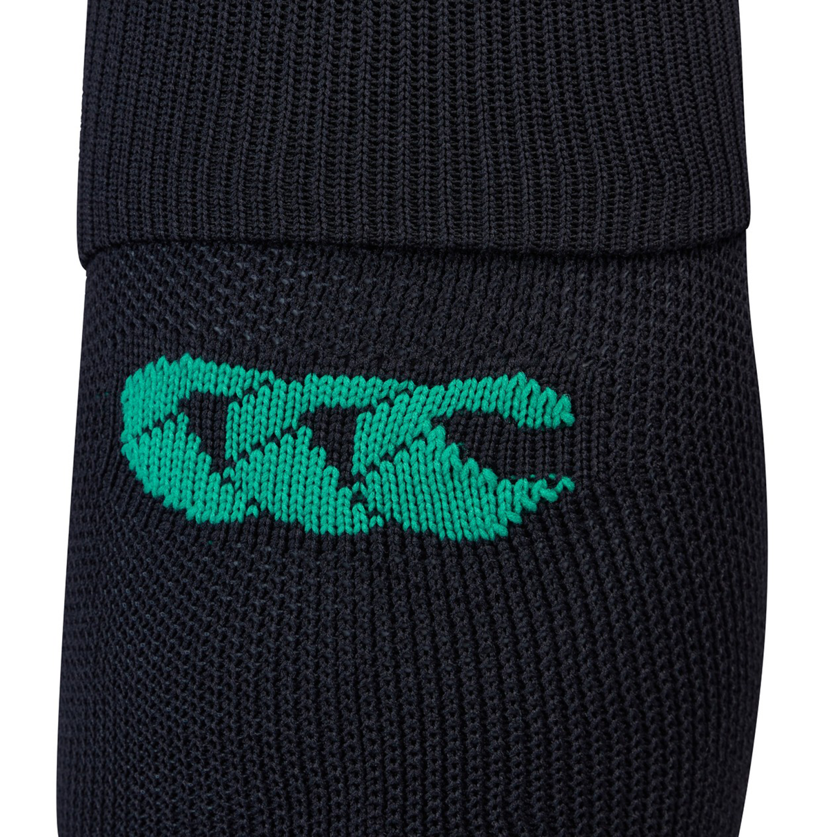 Close-up of the Ireland 25/26 Alternate Socks by Canterbury in black knit, featuring a green embroidered "CCC" logo and fast-drying yarn for enhanced comfort.