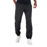 A man stands wearing dark Canterbury Tempo Vaposhield Dome Pant and white sneakers, focusing on the visible details and design of the pants.