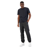 A young man wearing a casual dark outfit with a Canterbury Tempo logo on his shirt and Canterbury Vaposhield Dome Pants, standing confidently against a plain white background.