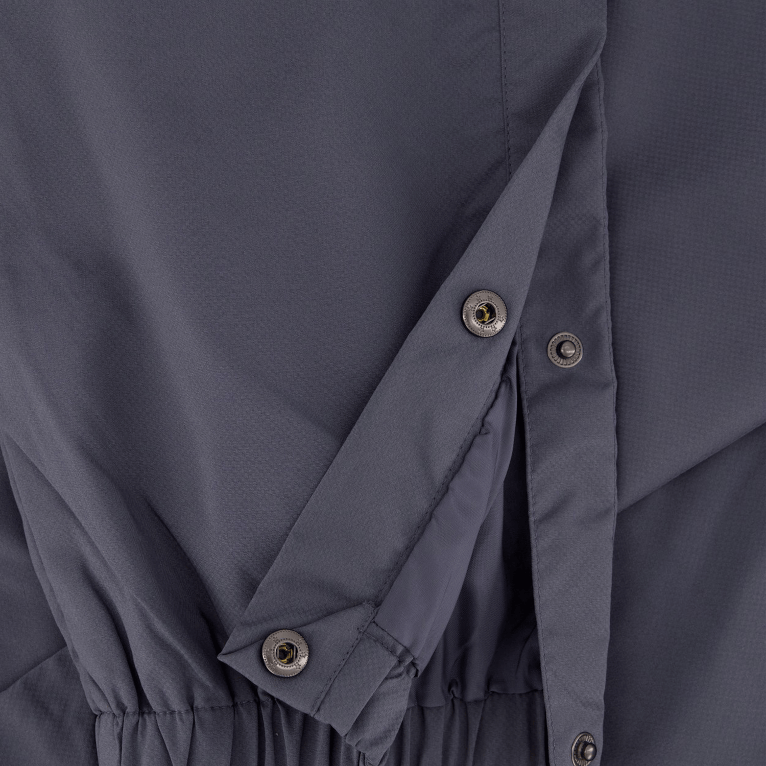 Close-up of the Canterbury Tempo Vaposhield Dome Pant, highlighting its gray fabric with a diagonal flap, buttons, and an elastic waistband at the bottom, reminiscent of lightweight track pants.