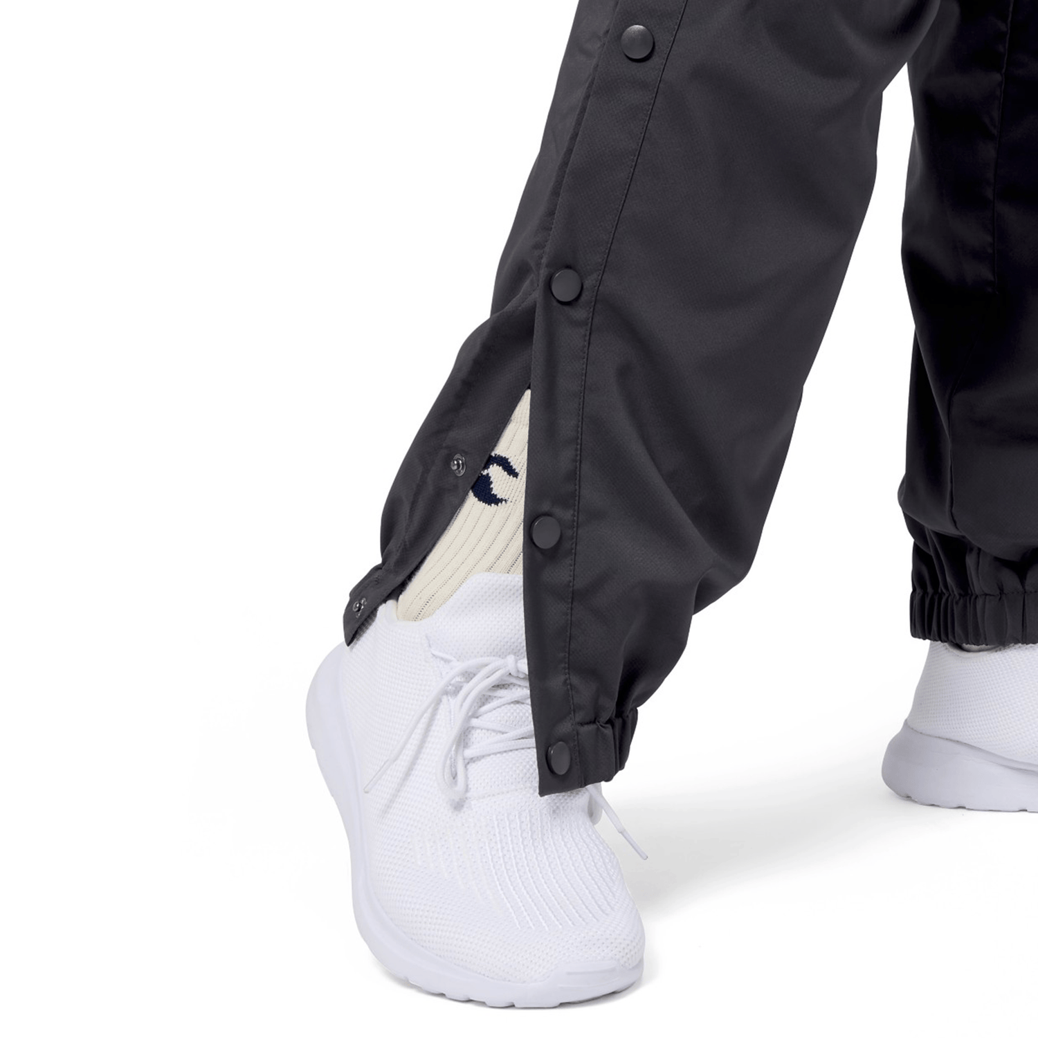 A person wearing the Canterbury Tempo Vaposhield Dome Pant with an elastic waistband and white knit sneakers, complemented by logo-adorned white socks.