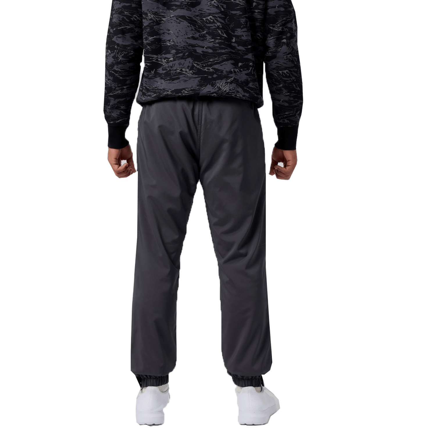 A person is wearing a black patterned jacket and Canterbury Tempo Vaposhield Dome Pant with an elastic waistband, paired with white sneakers, standing with their back to the camera against a white background.