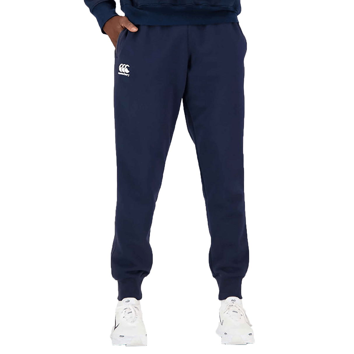 A person stands wearing Canterbury Anchor Fleece Pants and white sneakers, with a visible logo on the left thigh. Only the lower half of the body is shown.