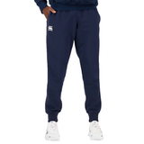 A person stands wearing Canterbury Anchor Fleece Pants and white sneakers, with a visible logo on the left thigh. Only the lower half of the body is shown.