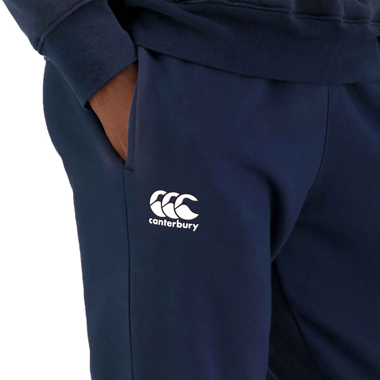 Close-up of navy blue Canterbury Anchor fleece pants with a logo on the left thigh and a hand in the pocket.