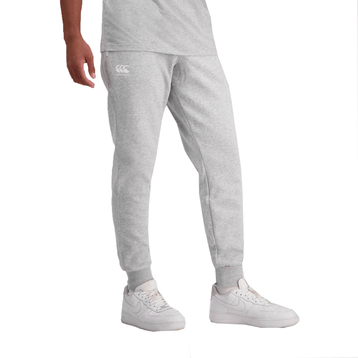 Lower half of a person wearing gray Canterbury Anchor Fleece Pants and white sneakers, standing against a white background.