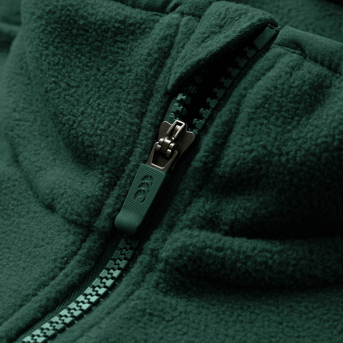 Close-up of the Canterbury Ireland 26 Retro Fleece 1/4 Zip, featuring its distinctive green fabric with a partially closed plastic zipper that highlights the texture and detailing of both the fleece and the zipper.