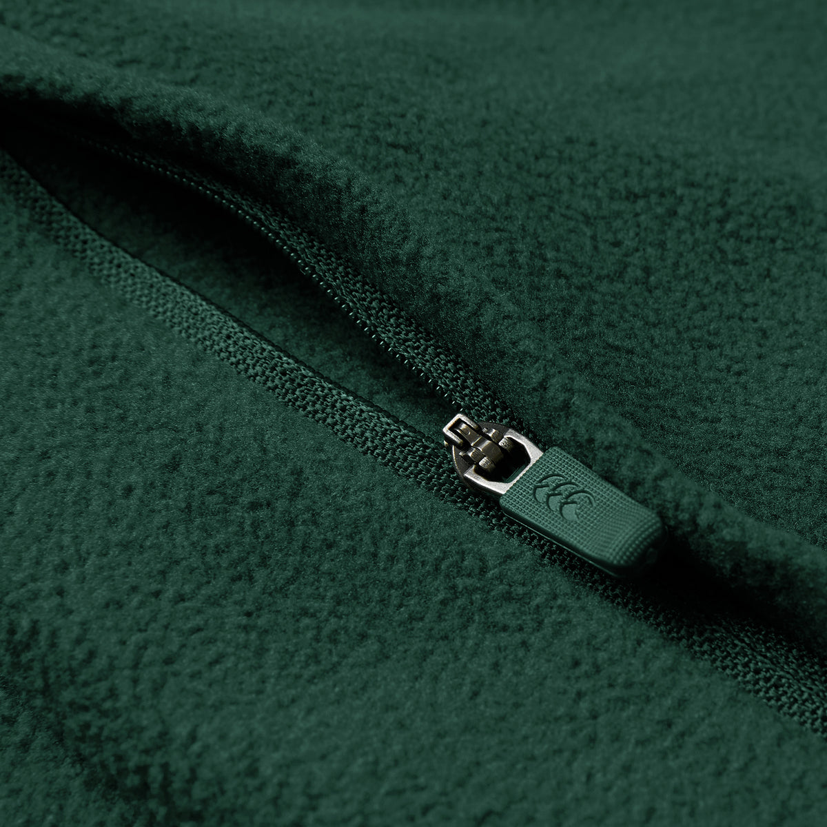 Close-up of the Ireland 26 Retro Fleece 1/4 Zip by Canterbury in green, showing the textured fleece fabric and a partially closed branded zipper pull.