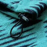 Close-up of the Ireland 26 Retro Fleece 1/4 Zip by Canterbury in teal and dark blue, featuring a drawstring with a plastic toggle adorned with a leaf design, reminiscent of classic retro rugby styles.