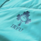 Close-up of a teal Ireland 26 Hybrid Padded Jacket by Canterbury, featuring the IRFU logo with a rugby ball and shamrock design printed above the letters “IRFU.”.