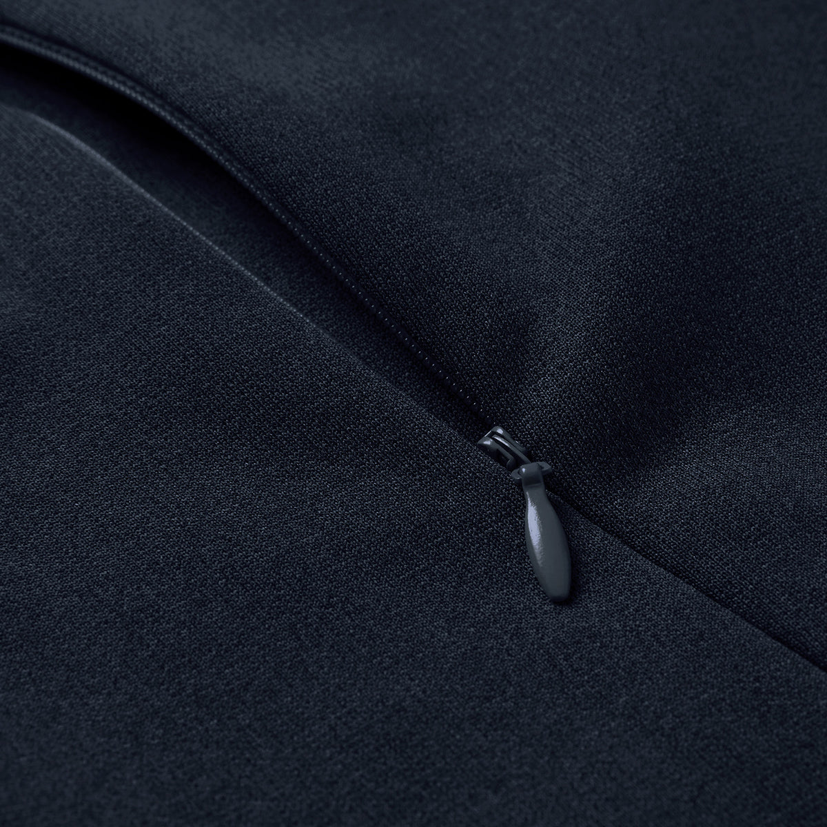 Close-up of a black zipper partially closed on dark fabric, highlighting the zipper pull and material texture on the Ireland 26 Hybrid Padded Jacket by Canterbury.