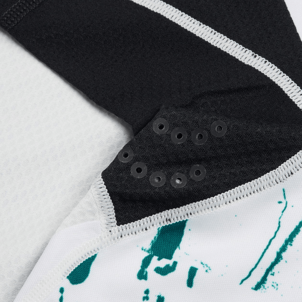 Close-up of a black and white fabric with green print on the Ireland 24 Alternate Test Jersey by Canterbury, featuring small black grommets arranged in a triangular pattern.